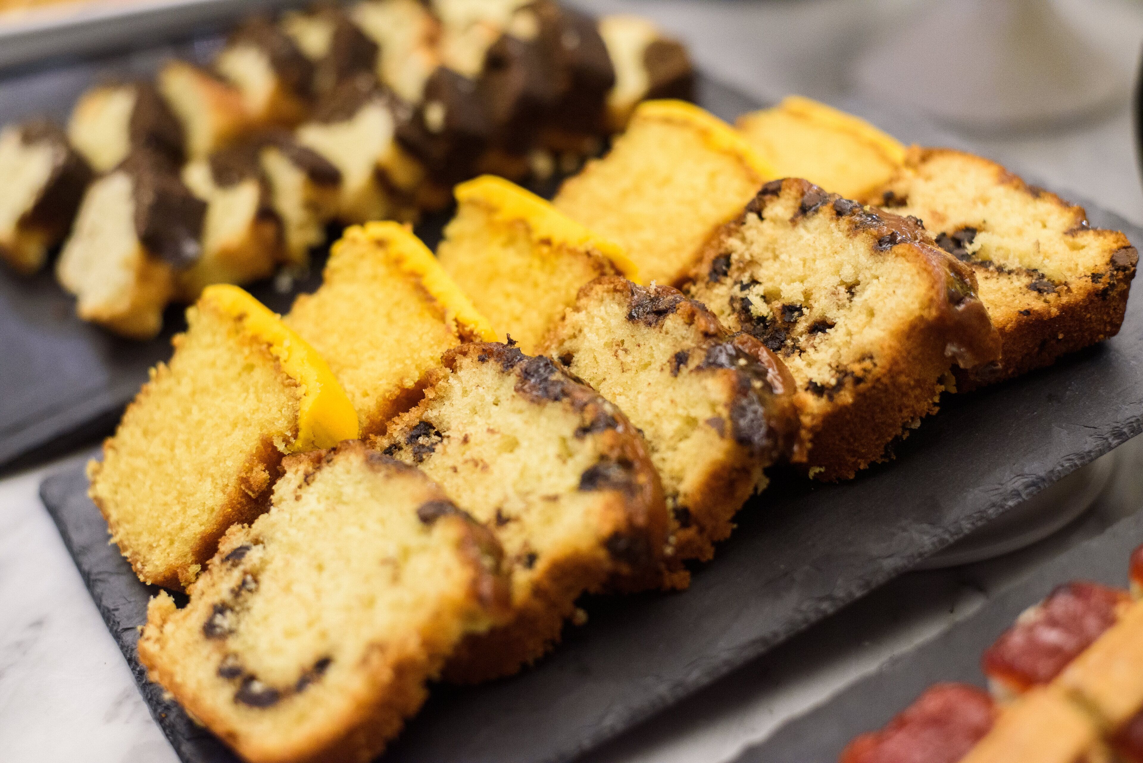 A slice of cake with a yellow crust and dark filling, placed on a slate serving board.