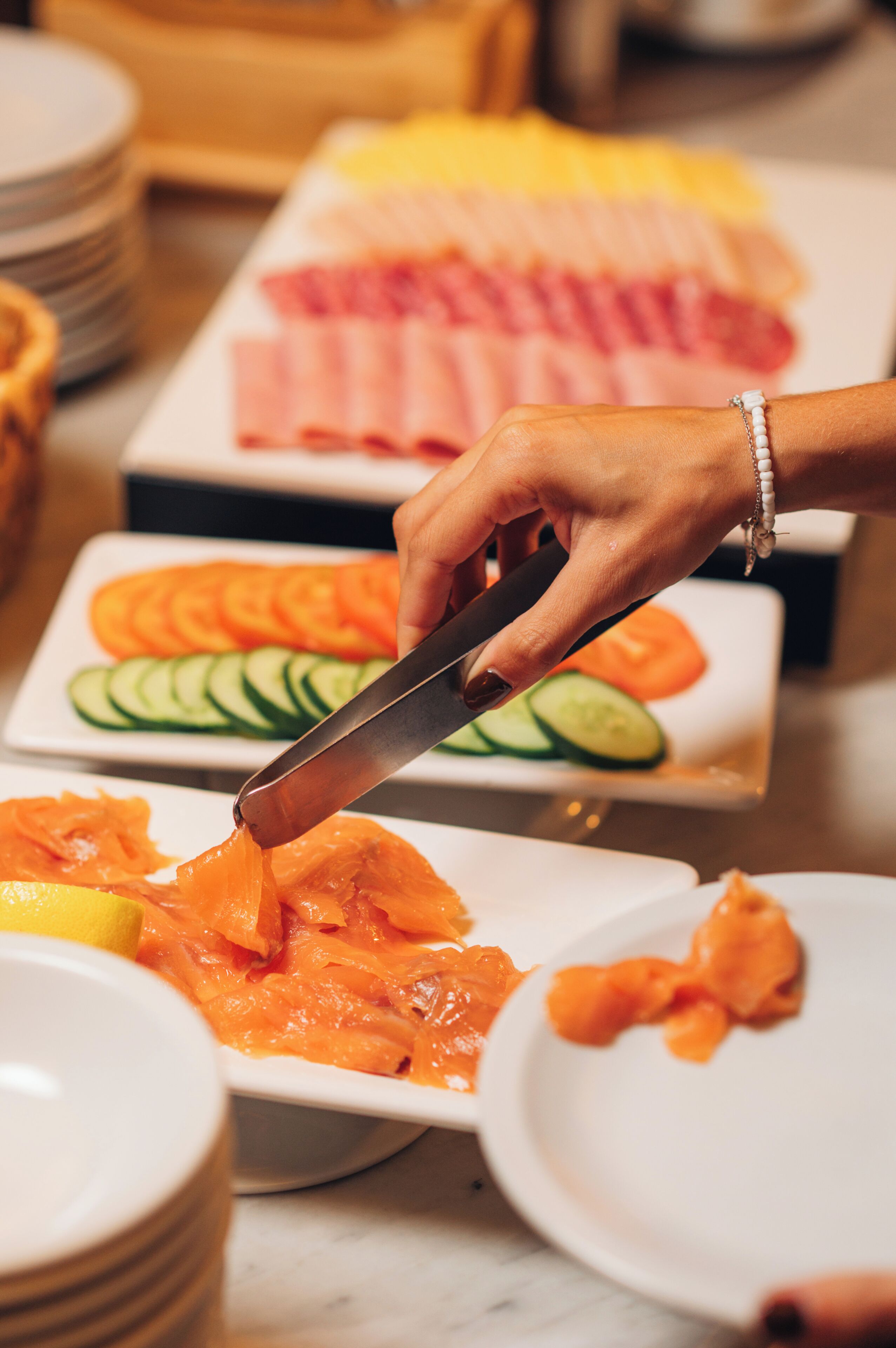 A person slicing salmon on a white plate.