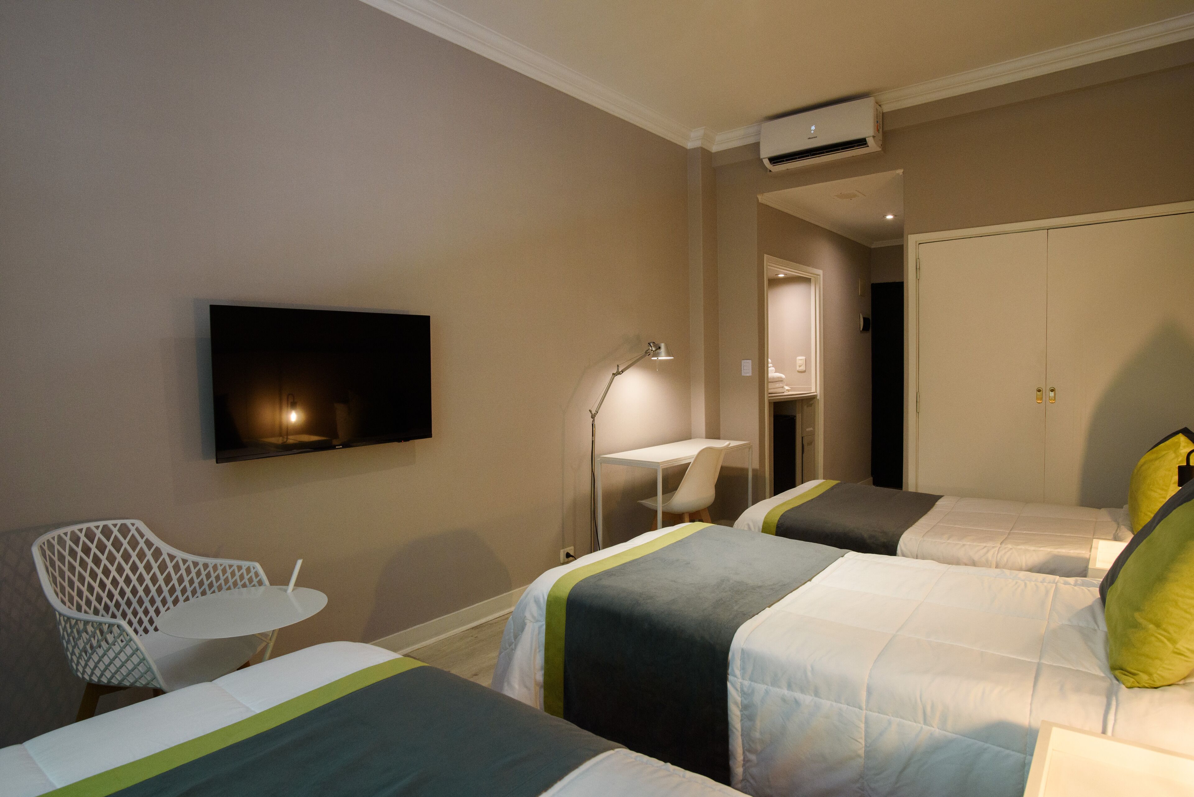 A hotel room with two beds, a TV, a desk, and a chair.