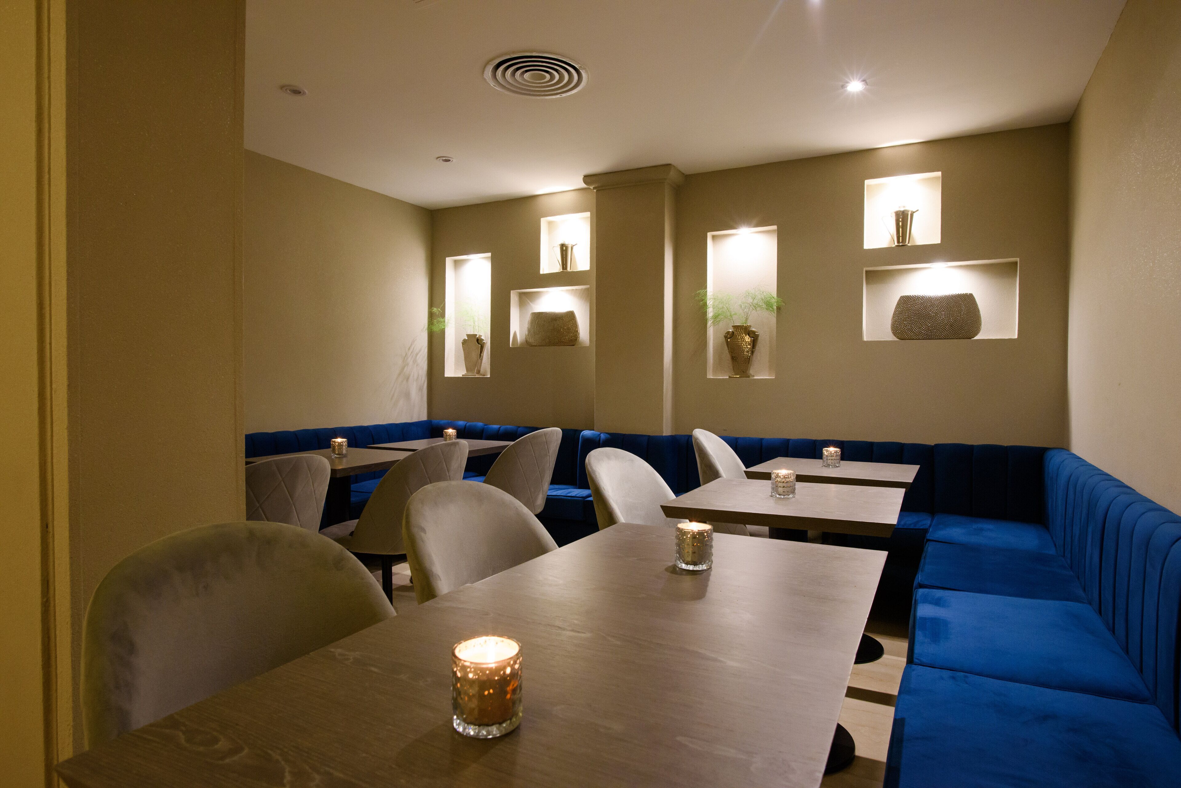 A restaurant with booths and tables, recessed lighting, and wall-mounted shelves with decorative items.