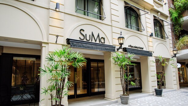 A hotel named 'SuMa' with a sign above the entrance, potted plants in front, and a patterned floor. - SuMa Recoleta Hotel (Buenos Aires)