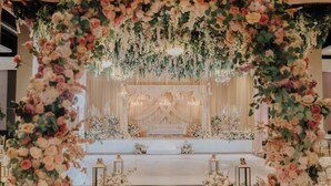 Um espaço interno com palco, decoração floral e lustres.