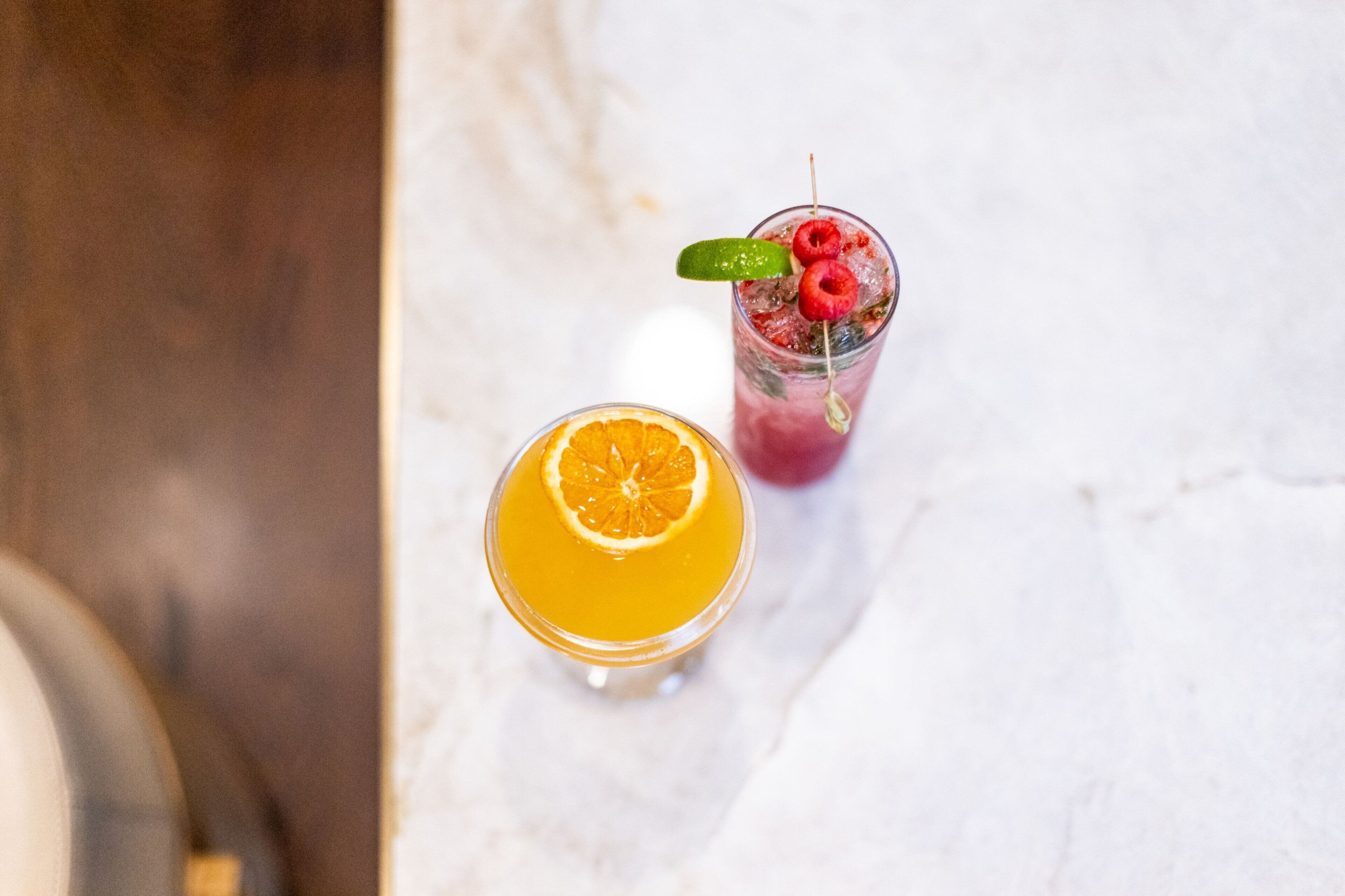 Two glasses of beverages on a marble surface.