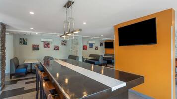 A modern restaurant with a long counter, bar stools, and a TV mounted on the wall.