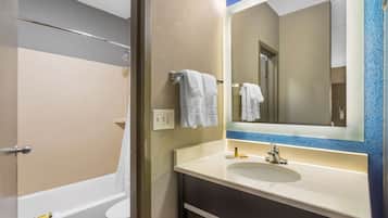 A bathroom with a bathtub, toilet, and a sink with a mirror.