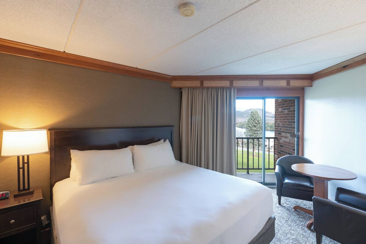 Une chambre d’hôtel avec un grand lit, un bureau, une chaise et une vue sur l’extérieur.