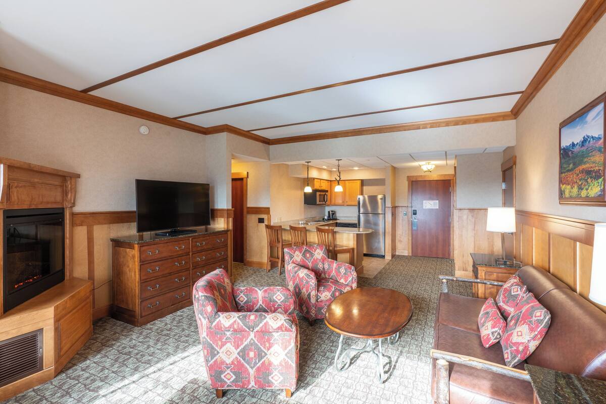 Une chambre d’hôtel dotée d’un coin salon, d’une kitchenette et d’une cheminée.