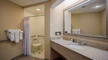 A hotel bathroom with a sink, mirror, and shower area.