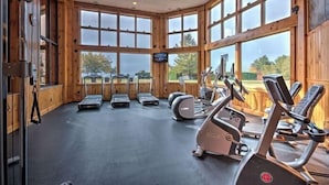 Een fitnessruimte met loopbanden, elliptische trainers en een grote wand met ramen.