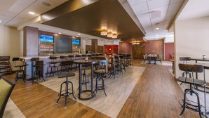 A spacious restaurant with high tables and stools, a bar area, and a television screen displaying a sports game. - Hotel MTK Mount Kisco (Mount Kisco)
