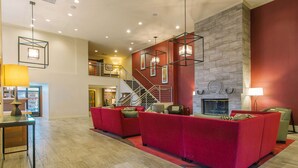 A spacious lobby with a red sofa set, a fireplace, and a staircase leading to an upper level. - Hotel MTK Mount Kisco (Mount Kisco)