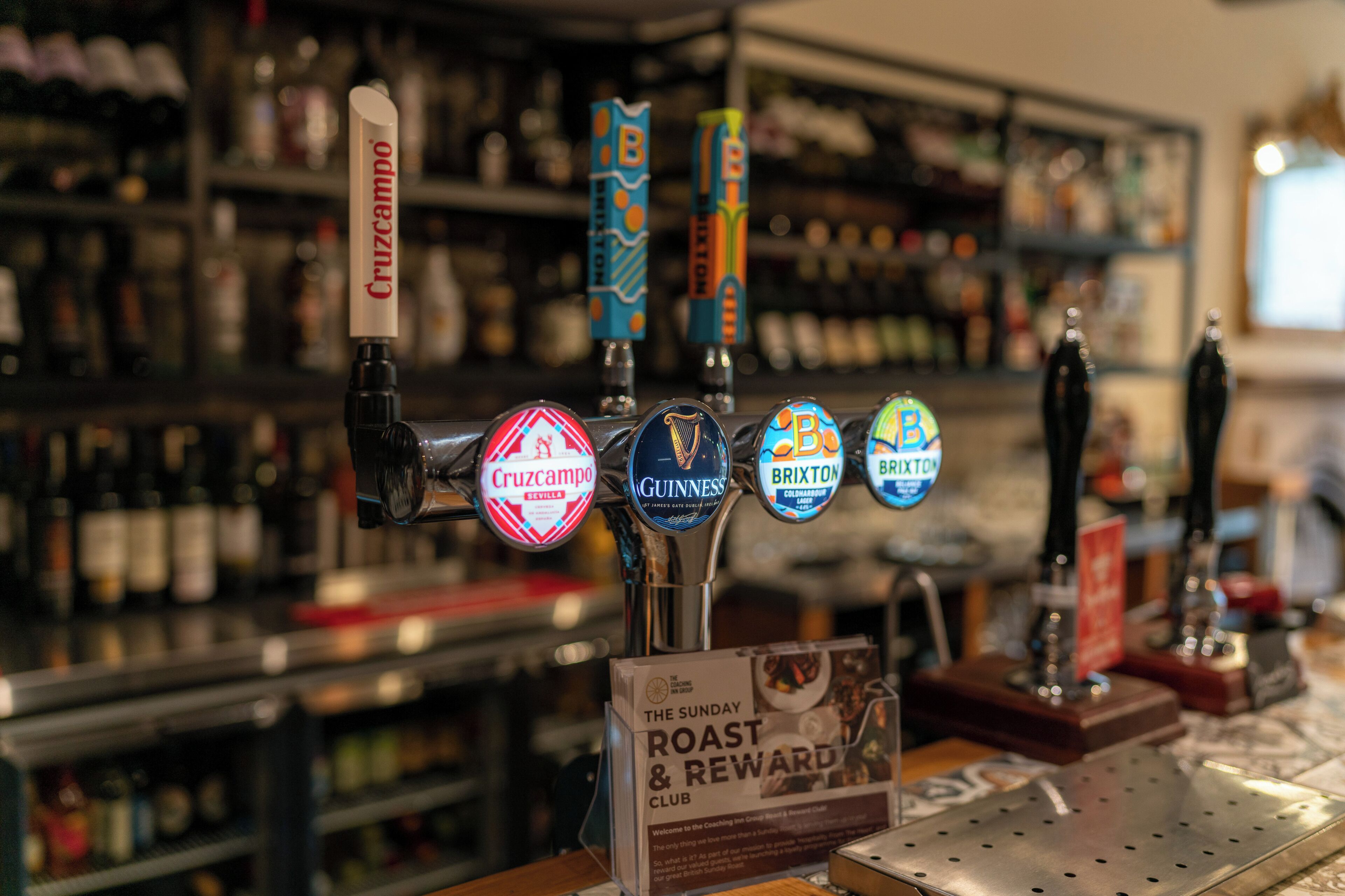A bar with multiple beer taps, including brands like Cruzcampo, Guinness, and Brixton.