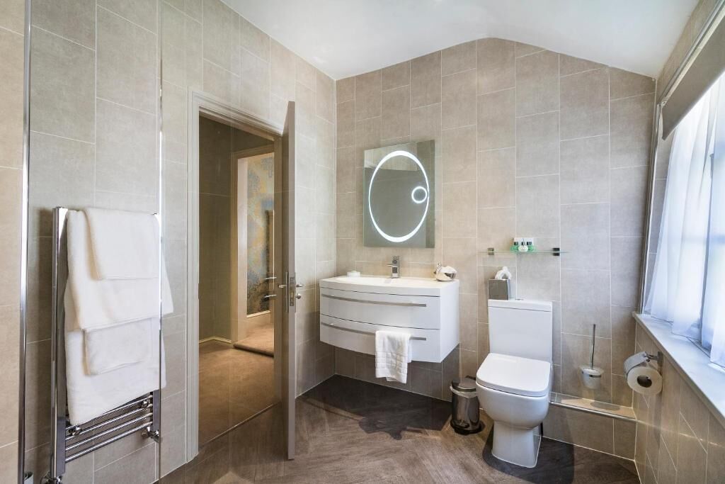 A modern bathroom with a glass shower enclosure, a vanity with a mirror, and a toilet.