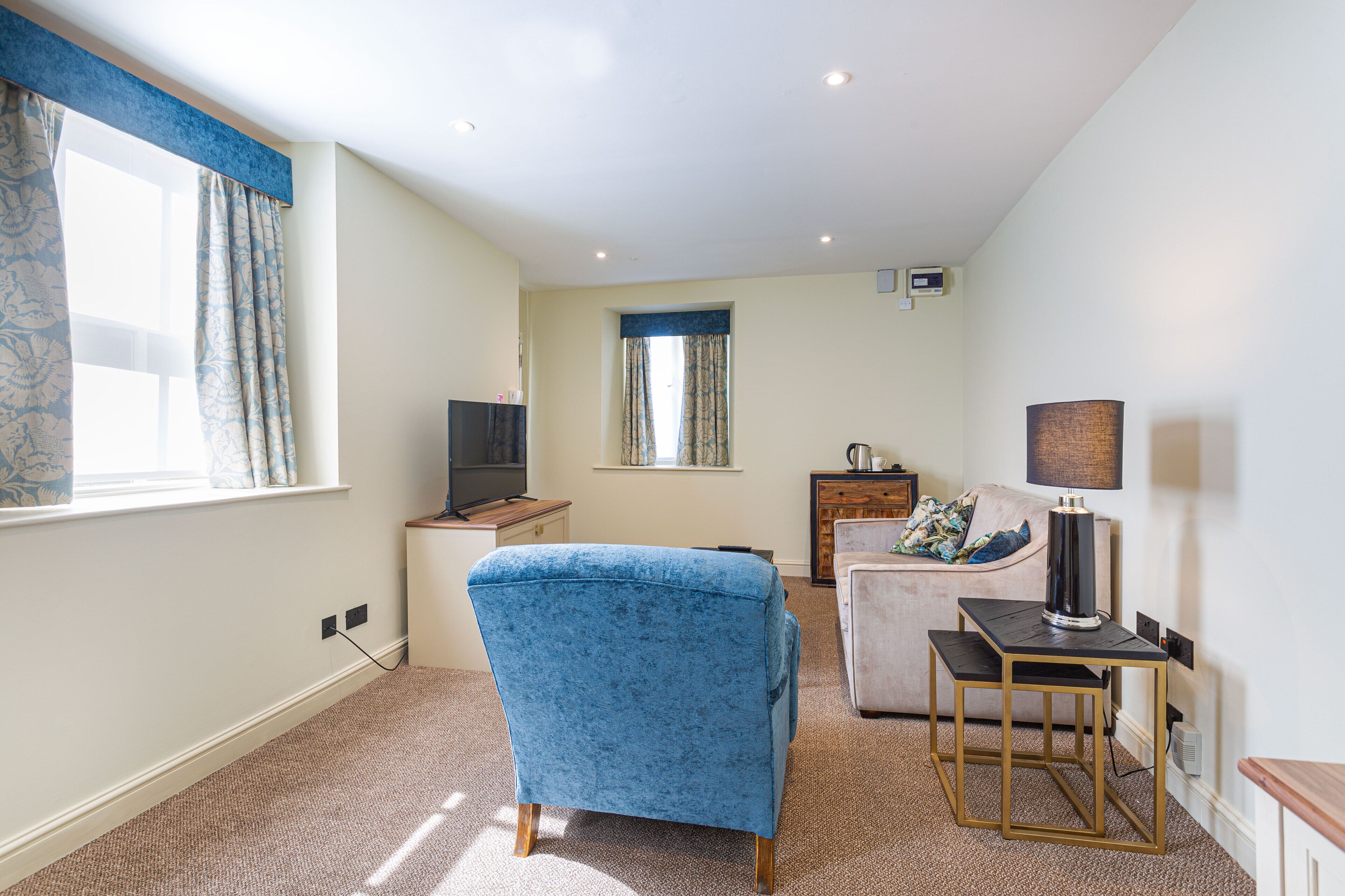 A living room with a blue armchair, a small table, a television, and a lamp.