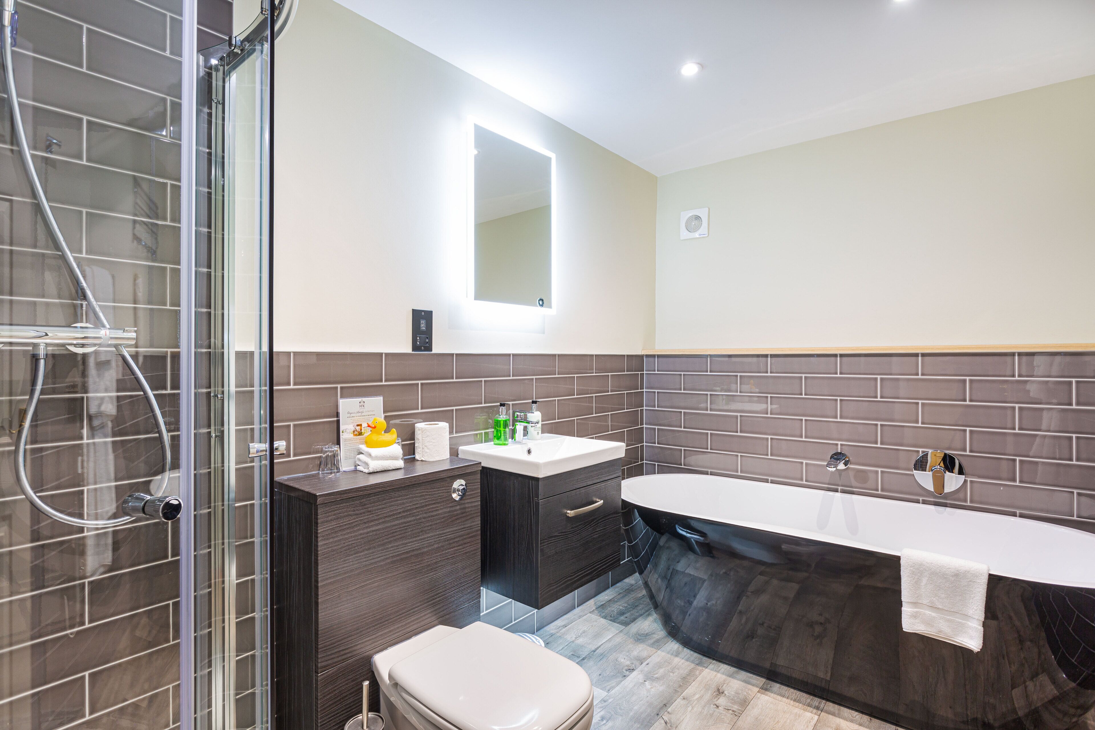 Un baño moderno con ducha acristalada, tocador con lavamanos y bañera independiente.