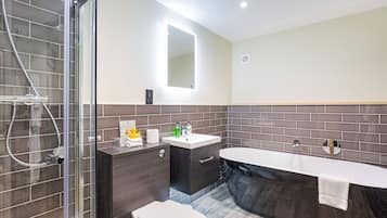 Un baño moderno con ducha acristalada, tocador con lavamanos y bañera independiente.