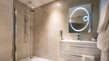 Un baño moderno con ducha de vidrio, tocador con espejo y perchero para toallas.