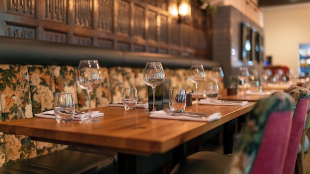 A restaurant interior with wooden tables, chairs, and a decorative wall. - The Swan Hotel Wells  (Wells)