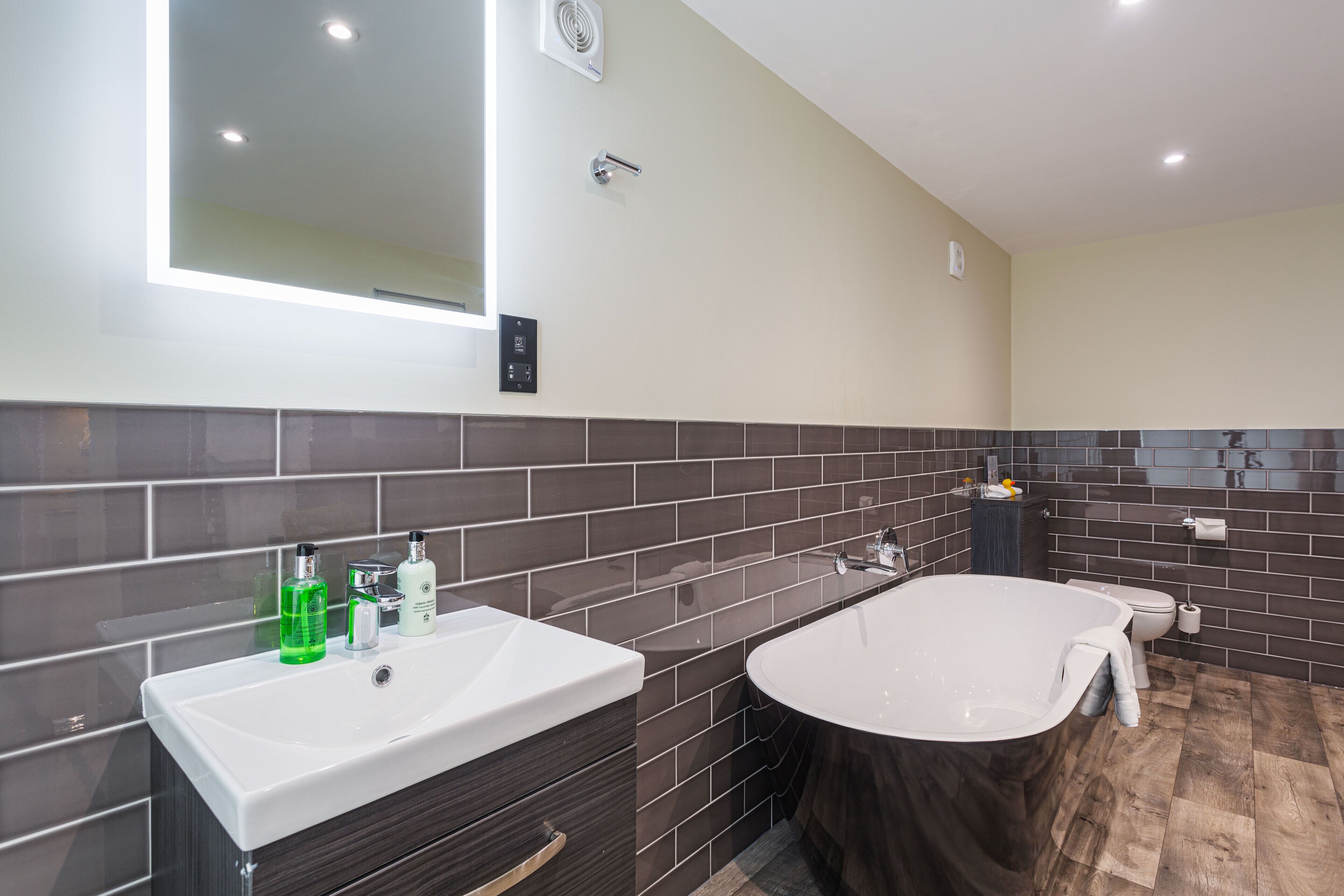A modern bathroom with a large bathtub, a white sink, and a mirror above the sink.