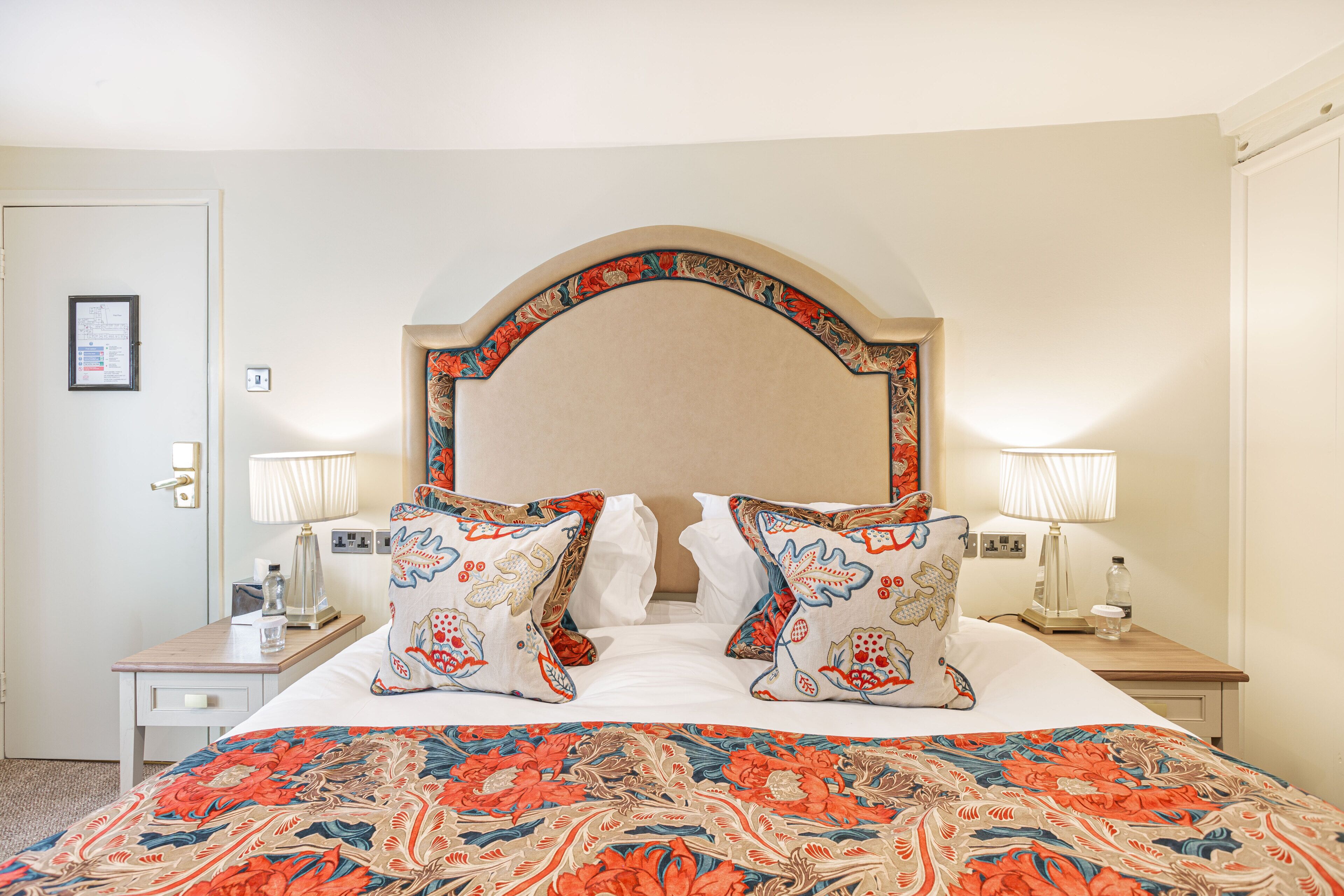 Una camera d'albergo con un letto grande, due lampade ai comodini, un comodino e un quadro appeso al muro.