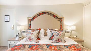 A hotel room with a large bed, two bedside lamps, a nightstand, and a framed picture on the wall.