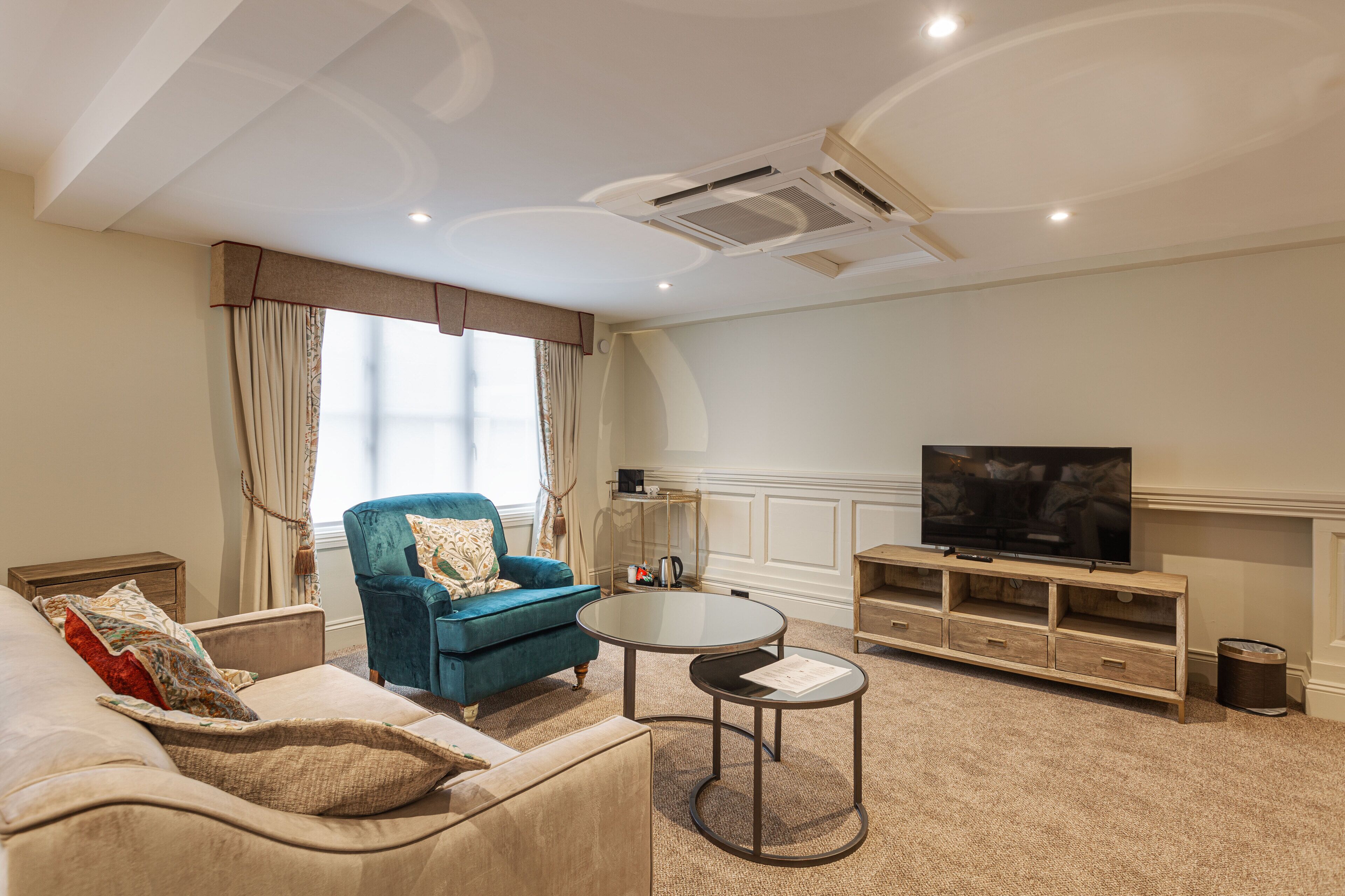 Una sala de estar con sofá, sillón, mesa de centro, televisor y mueble empotrado para entretenimiento.