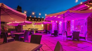 An outdoor patio area with tables and chairs, string lights, and umbrellas. - The Swan Hotel Wells  (Wells)
