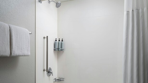 Un baño moderno con una bañera blanca, un cabezal de ducha y un perchero para toallas.