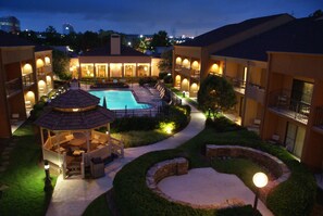 A hotel courtyard with a swimming pool, lounge chairs, and a gazebo.