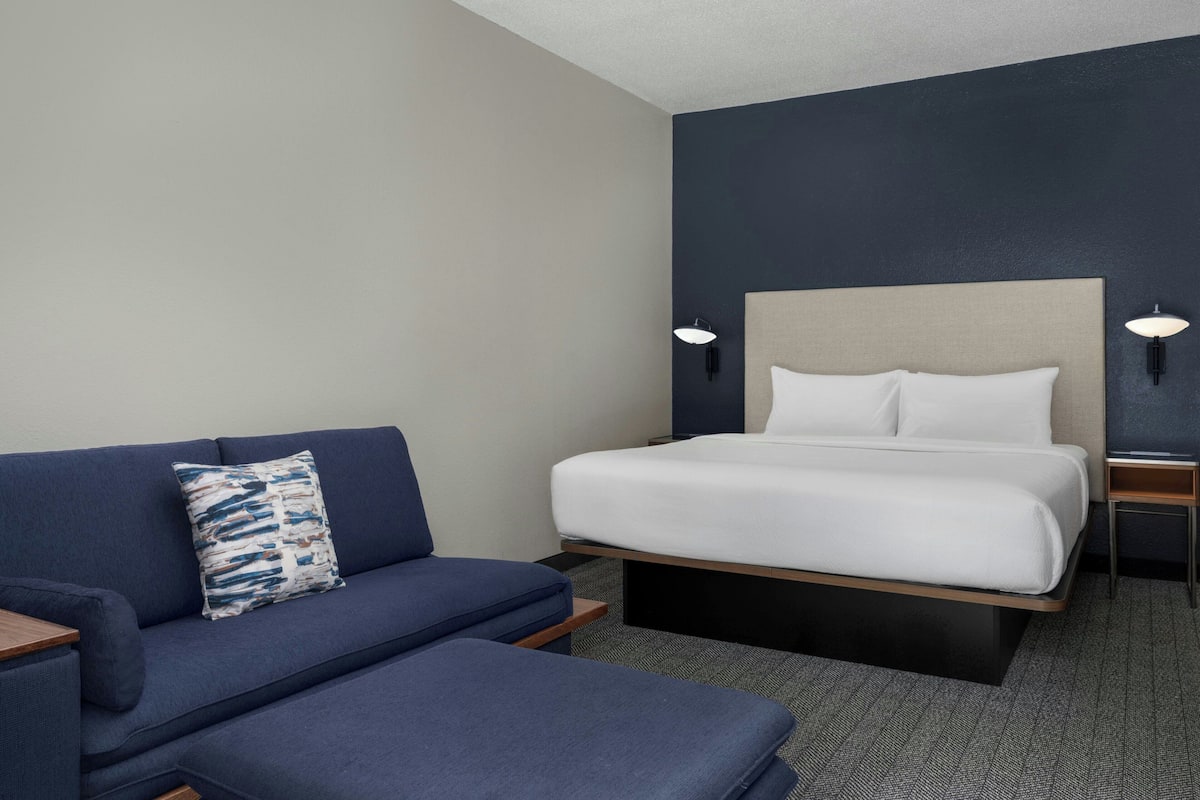 Una habitación de hotel moderna con cama, sofá y una mesita.