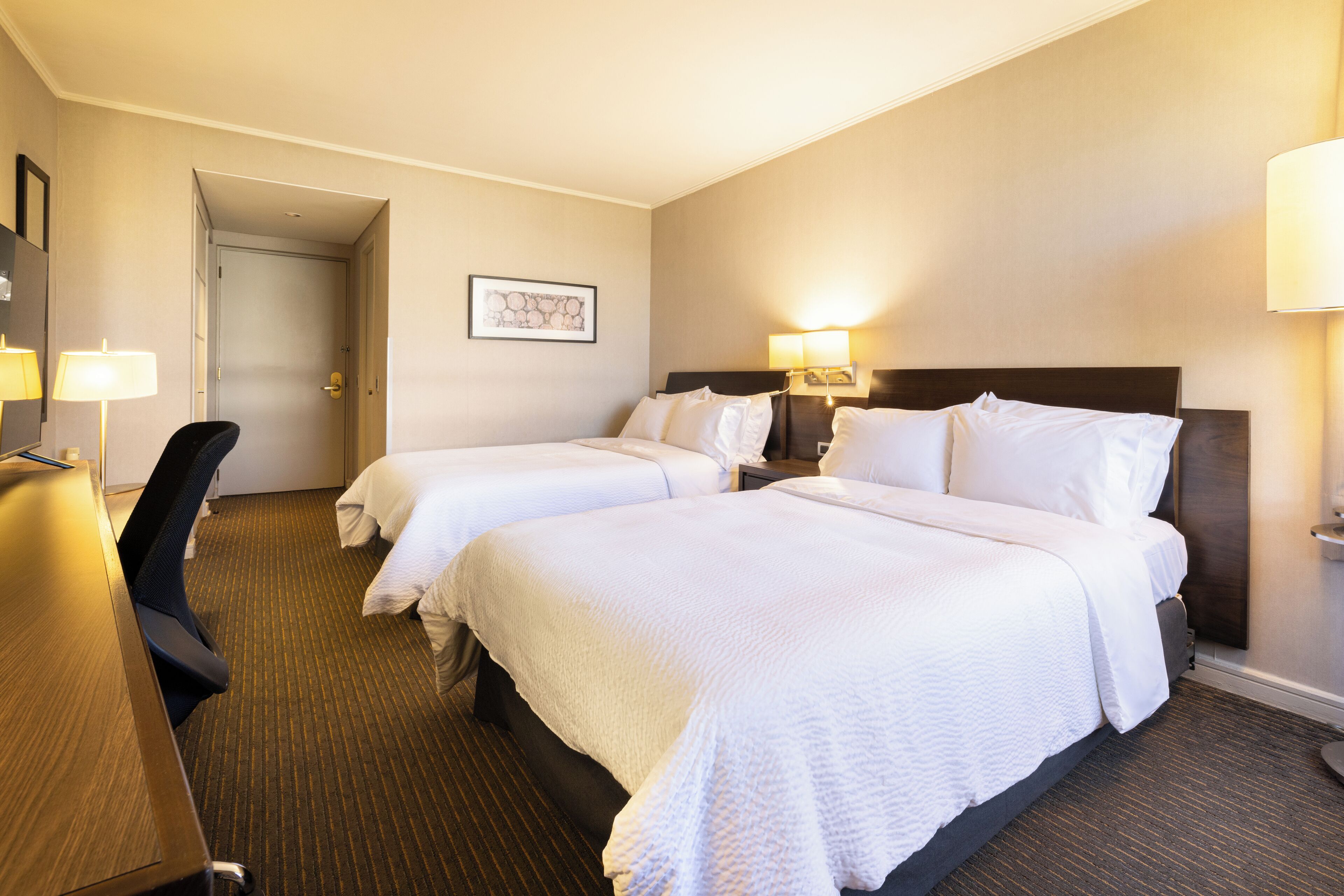 Ein Hotelzimmer mit zwei Betten, einem Schreibtisch und einem Stuhl.