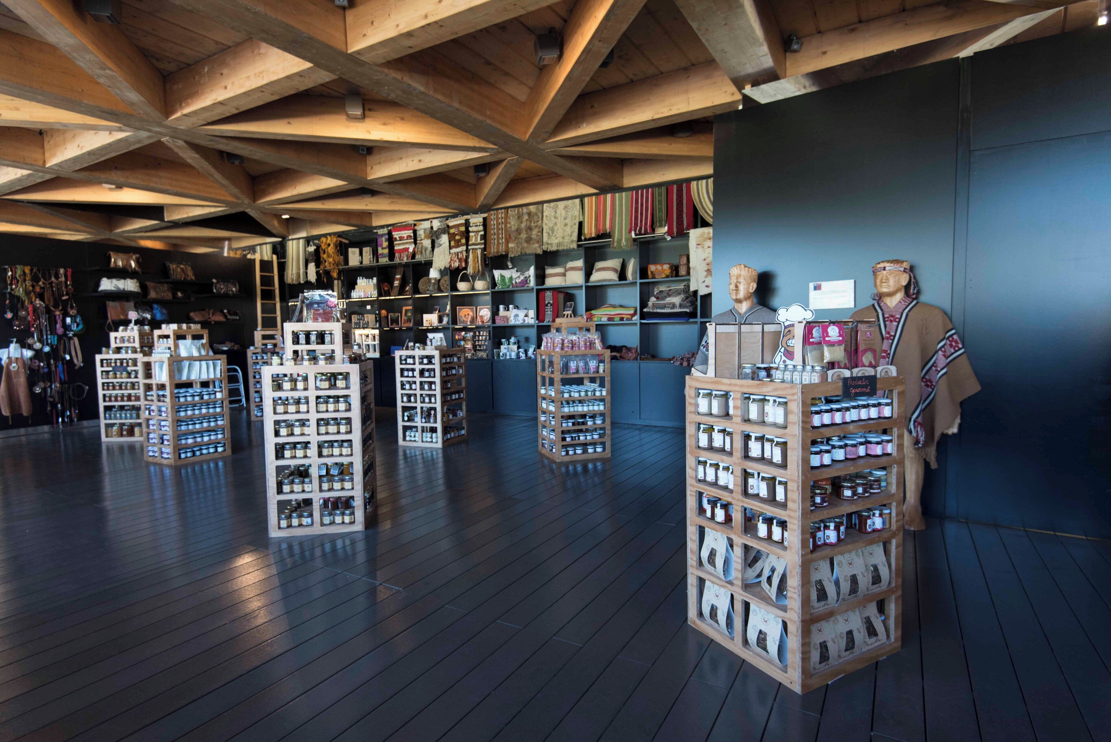 A store with wooden shelves displaying various items, including jars and textiles.