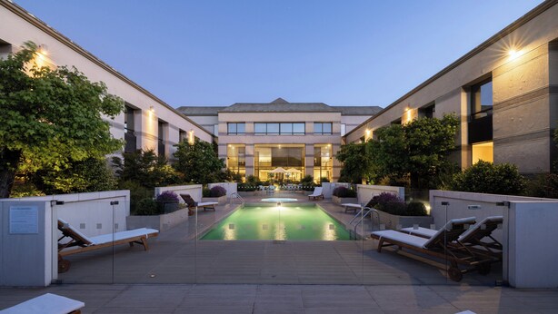 A poolside area with lounge chairs and a pool, surrounded by buildings with large windows and a covered walkway. - Holiday Inn Express Temuco by IHG (Temuco)