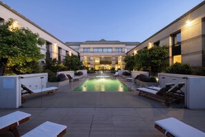 A poolside area with lounge chairs and a pool, surrounded by buildings with large windows and a covered walkway. - Holiday Inn Express Temuco by IHG (Temuco)