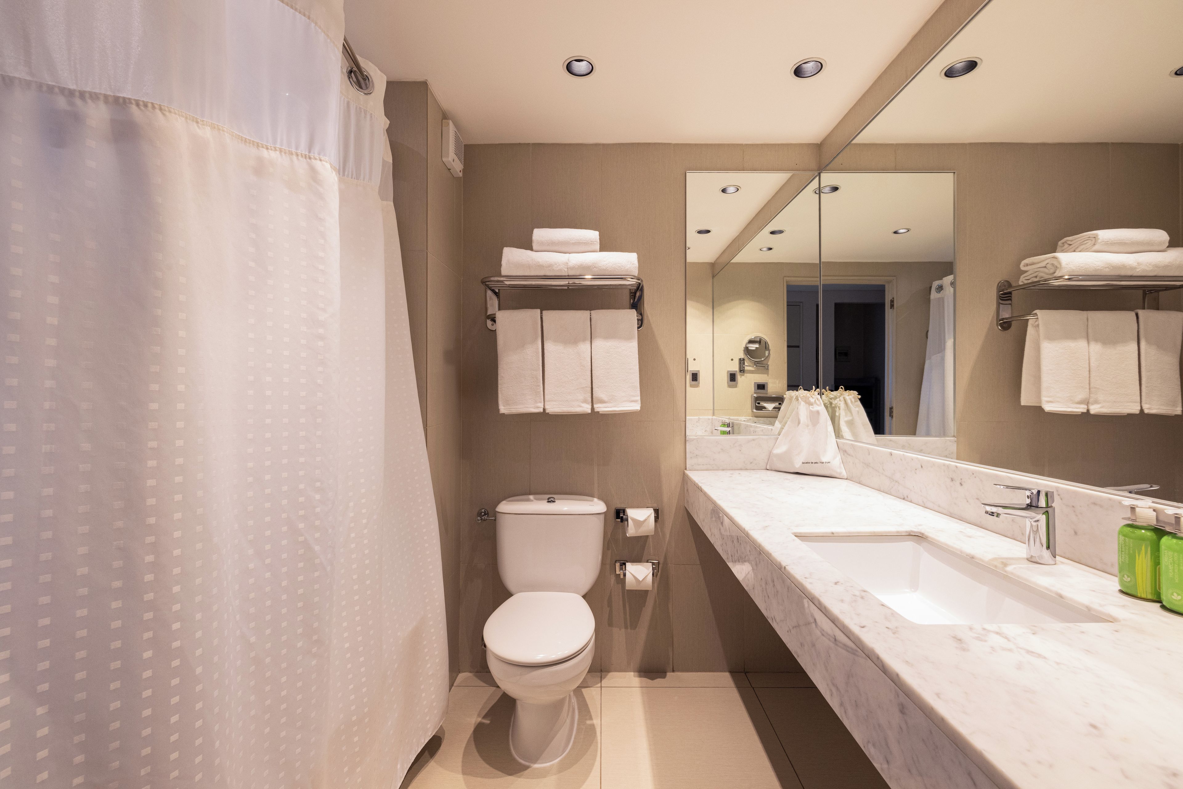 A modern bathroom with a toilet, a sink, and a mirror.