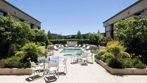 A pool area with lounge chairs and tables, surrounded by greenery and modern buildings. - Holiday Inn Express Temuco by IHG (Temuco)