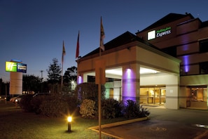 A Holiday Inn Express building with a well-lit entrance and multiple flags. - Holiday Inn Express Temuco by IHG (Temuco)