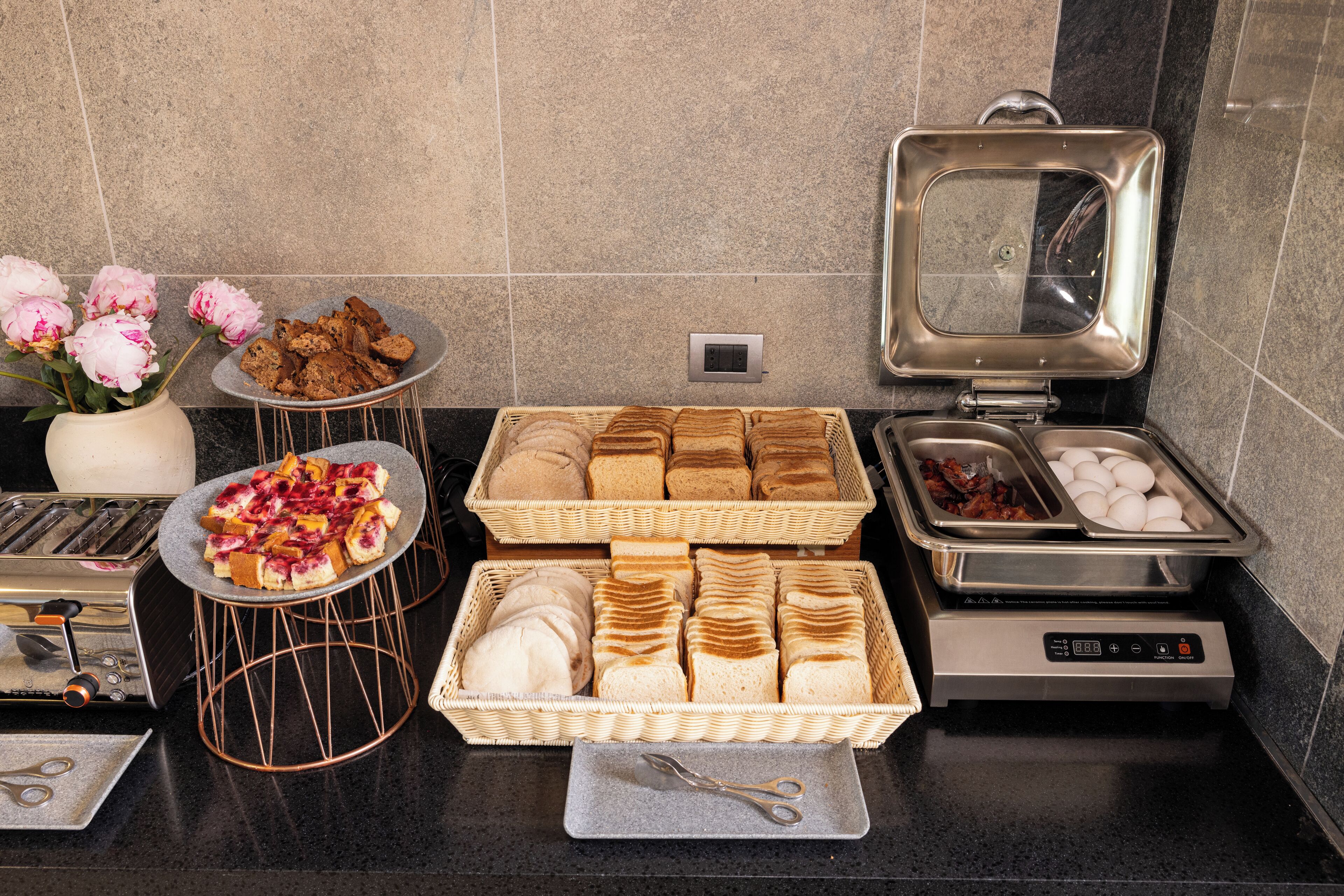 A breakfast buffet setup with bread, pastries, and eggs.