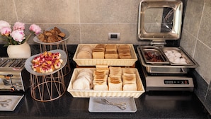 Una mesa de desayuno buffet con pan, pasteles y huevos.
