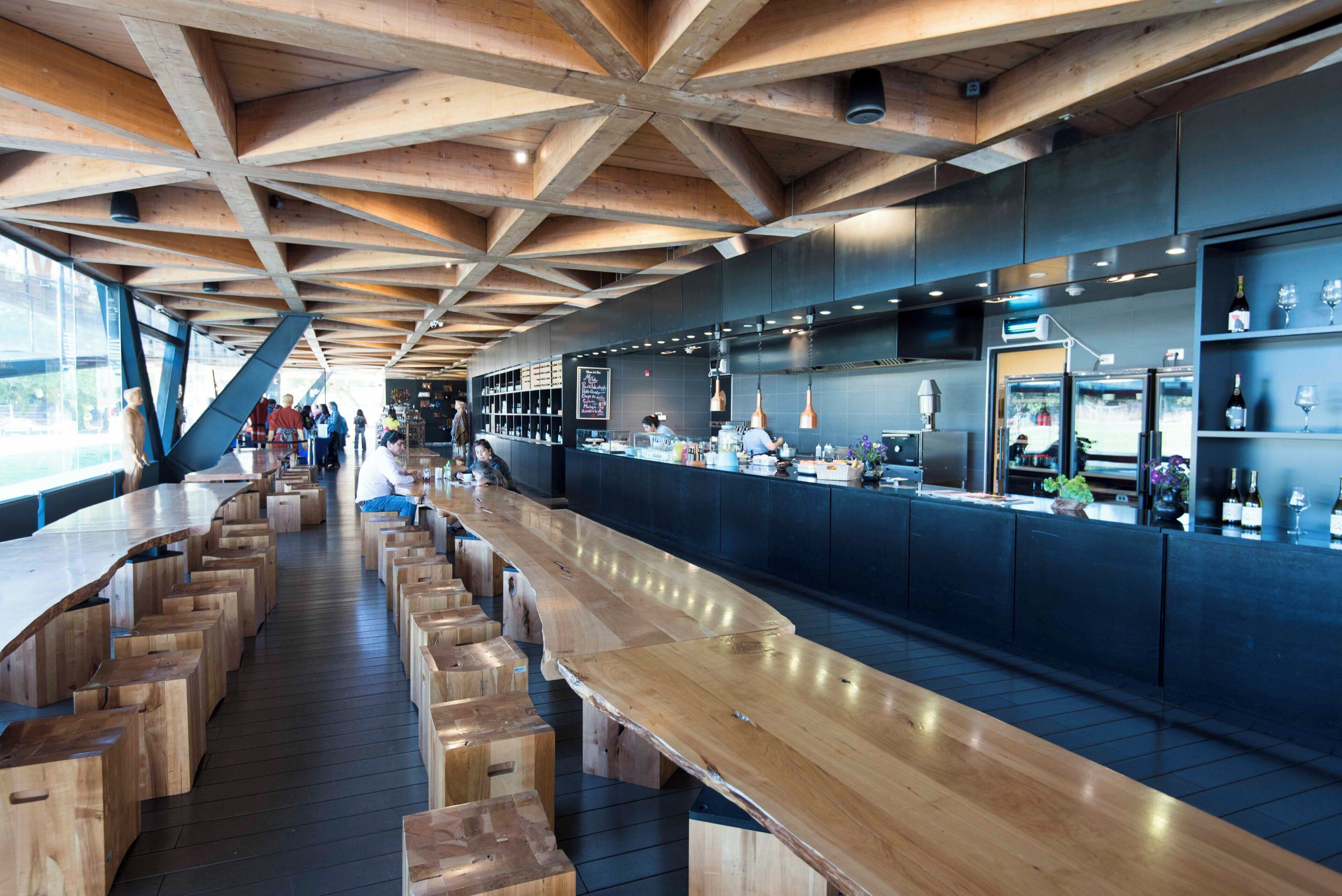 Un bar moderno con vigas de madera, asientos y una zona de cocina.