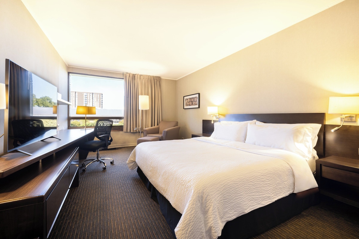 Ein Hotelzimmer mit Bett, Schreibtisch, Stuhl und Fernseher.