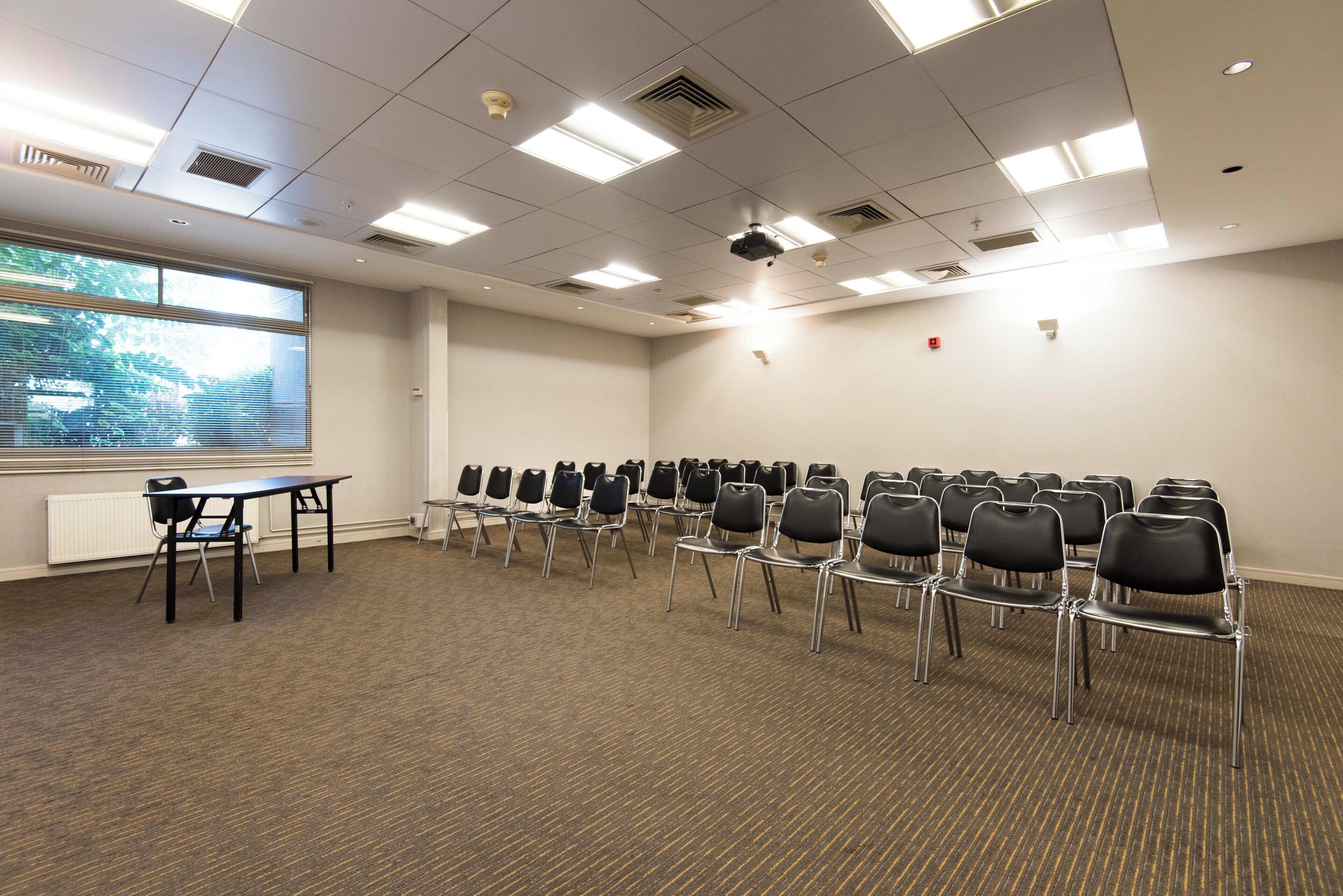 A conference room with rows of chairs, a projector, and a table.