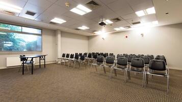 A conference room with rows of chairs, a projector, and a table.