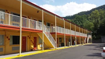Un motel con varias habitaciones, una escalera central y un estacionamiento.