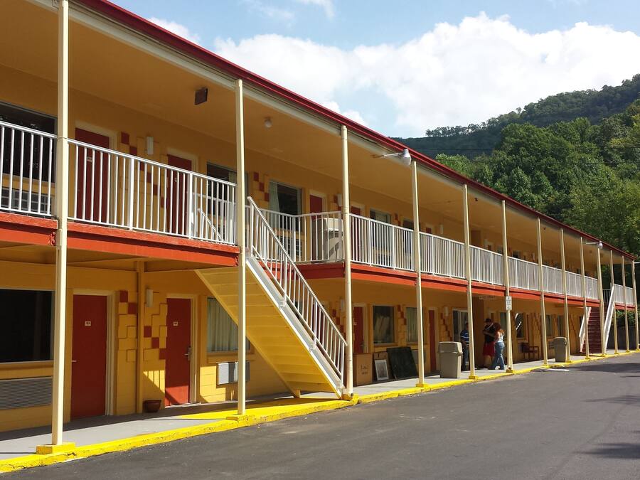 Un motel con varias habitaciones, una escalera central y un estacionamiento.