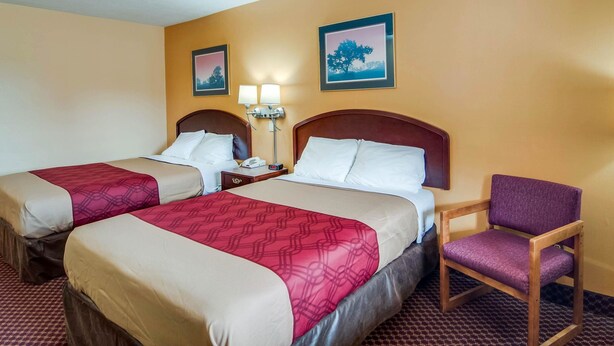 A hotel room with two beds, a chair, and two wall-mounted lamps. - Econo Lodge Near Bluefield College (Bluefield)