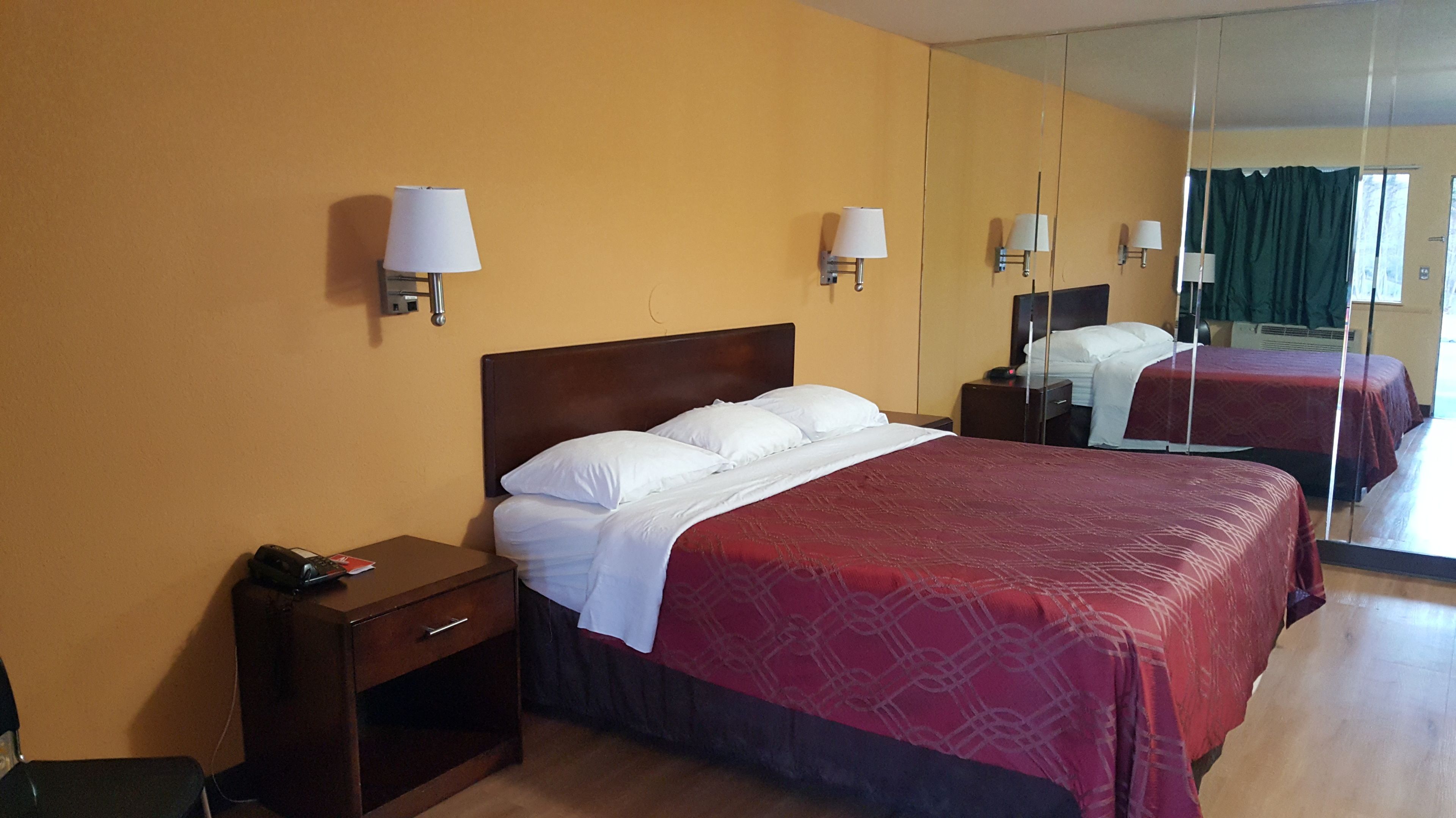 Ein Hotelzimmer mit einem großen Bett, zwei Nachttischen und einem Spiegel.