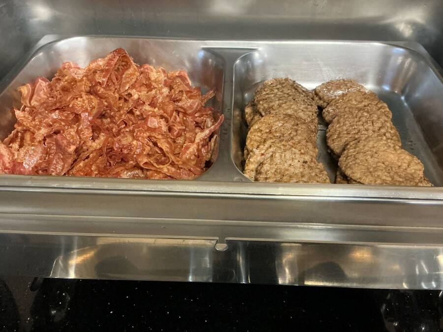 A stainless steel buffet with two sections: one with shredded meat and another with patties.
