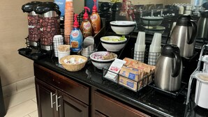 Ein Buffet mit Kaffeeautomaten, Kaffeetassen und Speisebehältern.