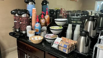 Ein Buffet mit Kaffeeautomaten, Kaffeetassen und Speisebehältern.